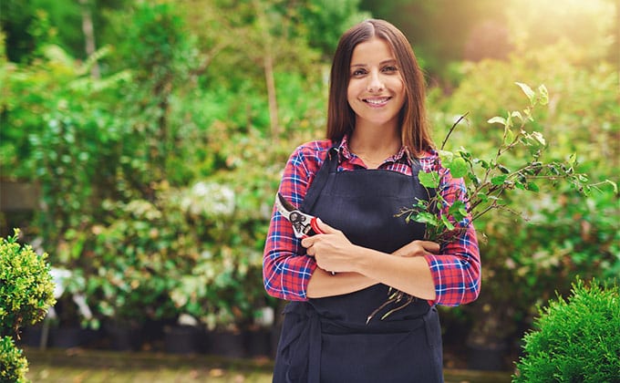 young woman pruning plants in garden